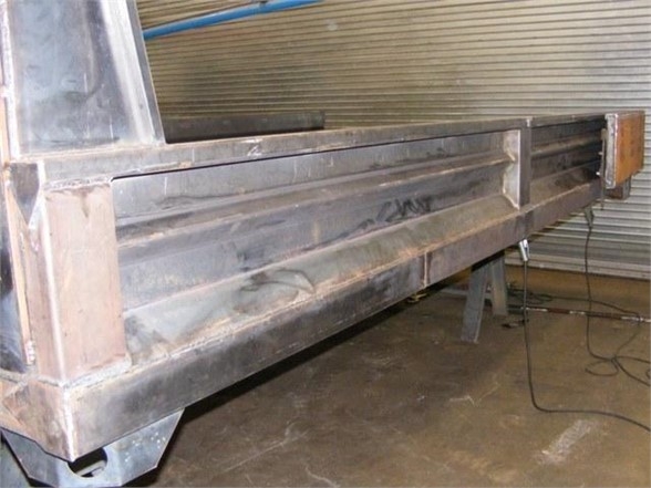 Dump body side panel of a 2024 Advanced Fabricators 14 ft truck bed showing metal construction and support brackets.