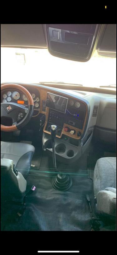 Interior view of a truck cab showing steering wheel, dashboard with gauges, center console, and gear shifter. No legible text visible.