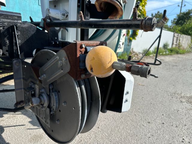 Vacuum truck wheel and reel system with yellow spherical reservoir cap and metal piping visible on Freightliner 108SD rear chassis.