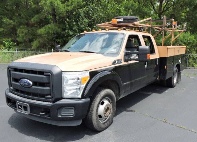 Ford F-350 utility truck with utility bed and equipment on the rear, beige and black color, front grille and headlamps visible.