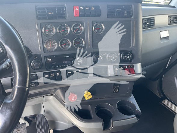 Kenworth T880 dashboard view showing multiple gauges, ignition area, cup holders, and pedal area.