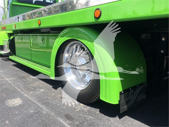 Green Peterbilt 337 tow truck side view with chrome wheel hub and fender, stock number J52310 label visible.