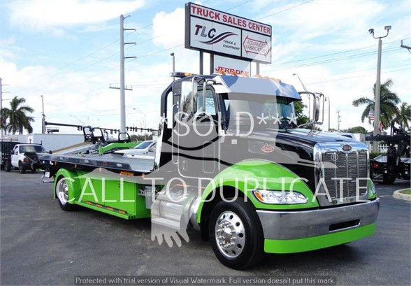2022 Peterbilt 337 tow truck in green and black, front bumper and cab visible, watermark covers center, dealership sign in background.