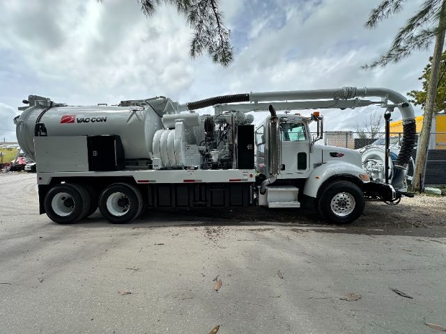 Vacuum truck side view with VAC-CON apparatus and extensive piping on Peterbilt 340 chassis.
