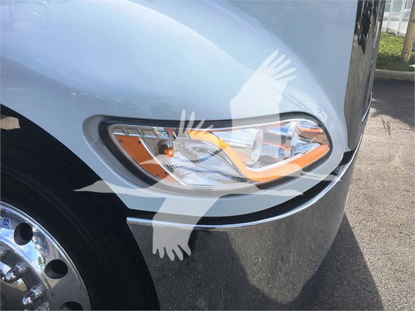 Truck headlight and front fender of a 2022 Peterbilt 337 with chrome wheel and light housing visible.