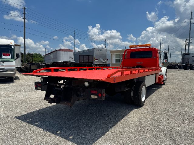 Red International flatbed tow truck rear view showing open deck and bumper lights.