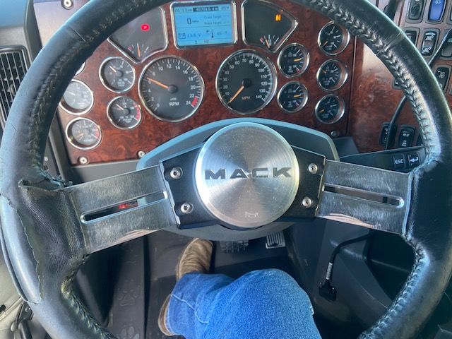 Mack CXU613 truck cab interior showing steering wheel and dashboard gauges.