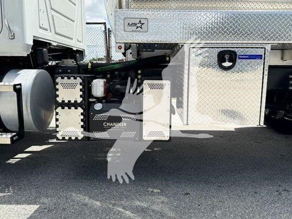 Chandler heavy-duty truck components undercarriage with diamond plate toolbox and fuel system; visible text includes 'CHANDLER' on a panel and 'US' logo on a sticker.