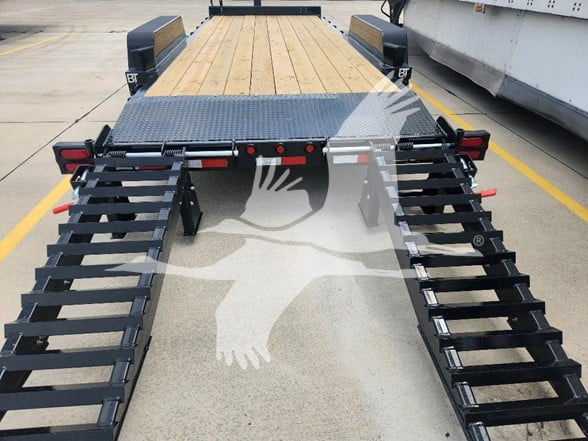 Flatbed trailer rear view with dual ramps extending outward, wood deck, black steel ramp sides, and safety lights; Behnke trailer with diamond plate and support structures.