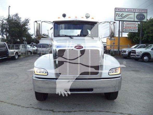 Peterbilt 337 front view showing chrome grille, bumper, and headlights at a truck lot.
