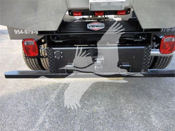 Rear view of a Ford F-600 truck bed with chipping equipment. Visible text includes VINCO-style emblem on a toolbox, left and right rear tail lights, and a phone-like number 954-979-9X along the chassis.