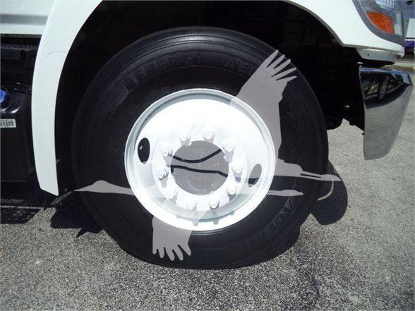 Industrial truck wheel and tire close-up on a white Hino 268A dump truck showing steel wheel with lug nuts.
