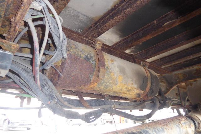 Underbody of Freightliner M2 106 showing rusted frame components and wiring harnesses.