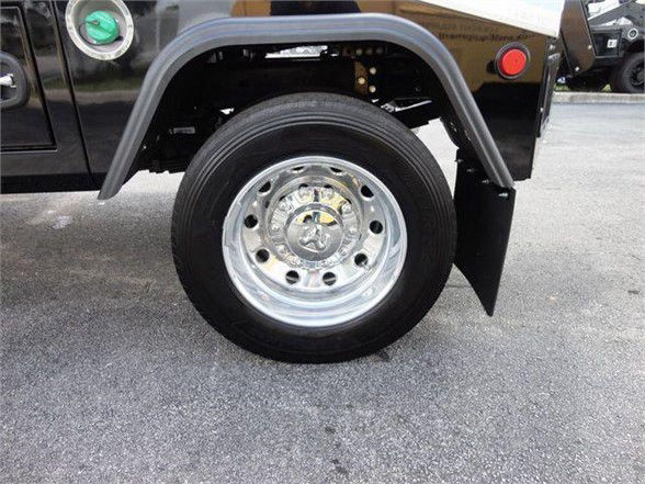 Ram 4500 HD wheel and fender showing polished steel wheel and tire, with black fender flare and green and red caps visible in background.