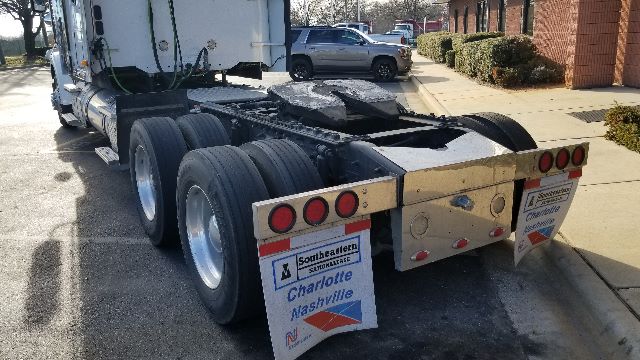 Freightliner Coronado 132 tractor rear view showing dual rear axles and mud flaps with center-mounted hitch, dealership signs visible.