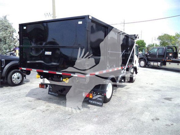 Isuzu NRR refuse truck dump bed, rear view with black body, white rear wheels, reflective tape, and tail lights visible.