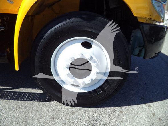 Truck wheel and partial fender of a yellow 2019 International DURASTAR 4300 in-service with visible tire and white steel rim.