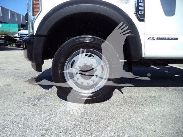Front portion of a white Ford F-550 dump truck showing the front wheel and fender with Ford emblem and badge text along the side.