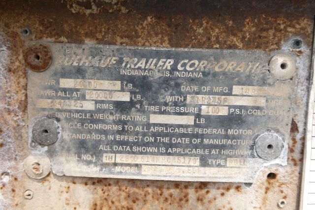Vanishingly legible data plate on a rusted surface with Vehicle Manufacturer Plate reading 'Fruehauf Trailer Corp' and various weight and tire specifications.