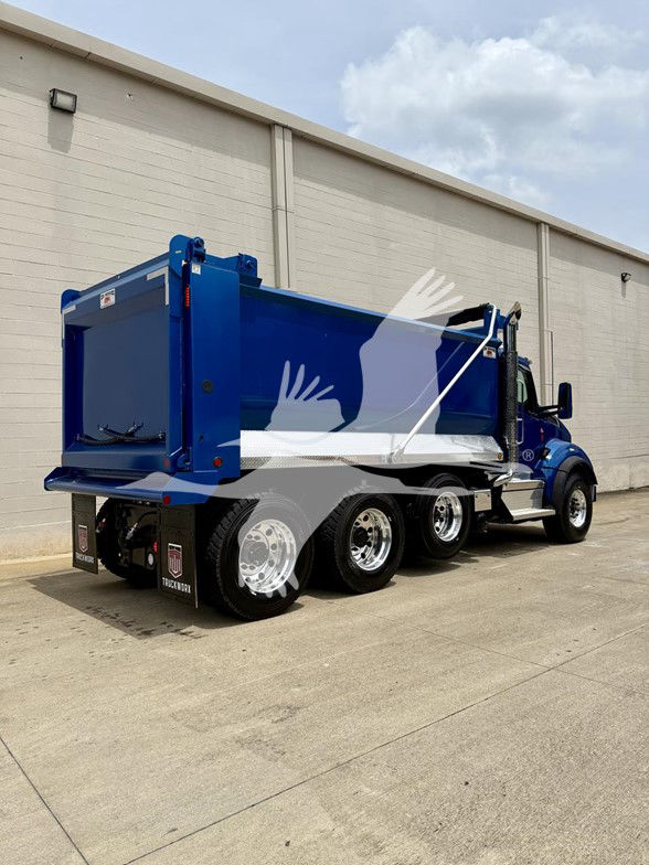 Blue Kenworth T880 dump truck side rear showing dump bed, dual rear wheels, reflective tape, and chrome wheels.