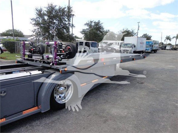 Peterbilt 337 lowboy trailer showing car transport equipment and purple wheel ramps, front wheel and side mirrors visible.