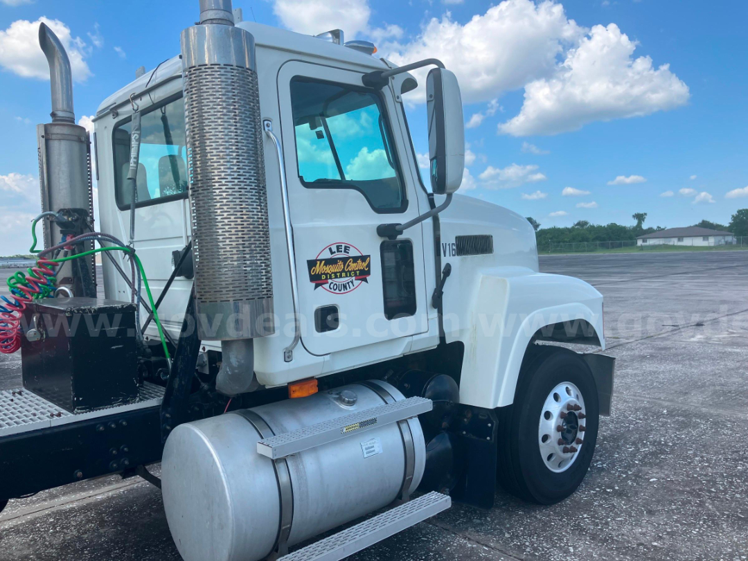 Cab and chassis truck side showing fuel tank and exhaust stack with Lee Mosquito Control District sticker on door.