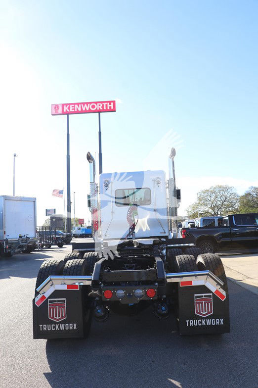 Kenworth W900L truck rear view showing back of cab and dual rear axles with mud flaps labeled TRUCKWORX, in a dealership lot.