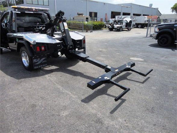 Tow truck bed with hydraulic lift and front hitch in a dealership lot. RAM 4500 HD SLT branding not visible.