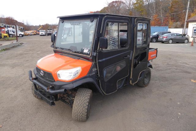 Kubota RTV-X1140 utility vehicle with orange hood and black body, side view showing windshield, doors, and off-road tires.