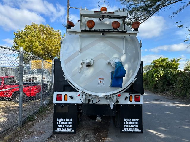Rear view of a white vacuum truck with vent hoses and safety lights, blue inlet hose connected at rear, orange beacon lights on top.