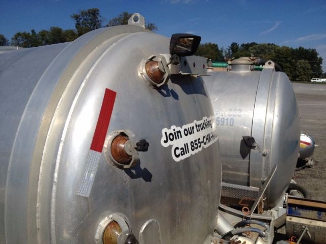 Two large cylindrical metal vacuum tanks with fittings and labels.