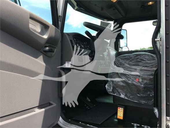 Peterbilt 337 truck cab interior seen from doorway; fabric-covered seat with plastic wrap; steering wheel and dashboard visible; no visible model badges readable.