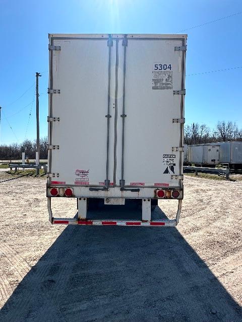Rear view of a white 2015 Wabash DuraPlate dry van trailer with double rear doors, taillights, and safety stickers.