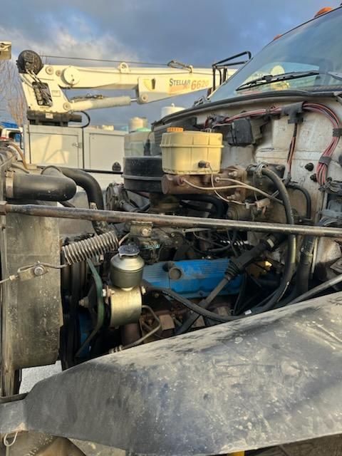 2011 Chevrolet Kodiak/ truck engine bay with visible components including brake fluid reservoir, air intake, hoses, and wiring. Engine bay shows components and surrounding truck with windshield and hood.