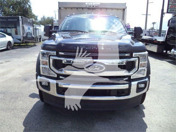 Front view of a 2022 Ford F-550 heavy-duty truck with chrome grille and large bumper, stock number F5504X4ALUMDMP visible in listing details.