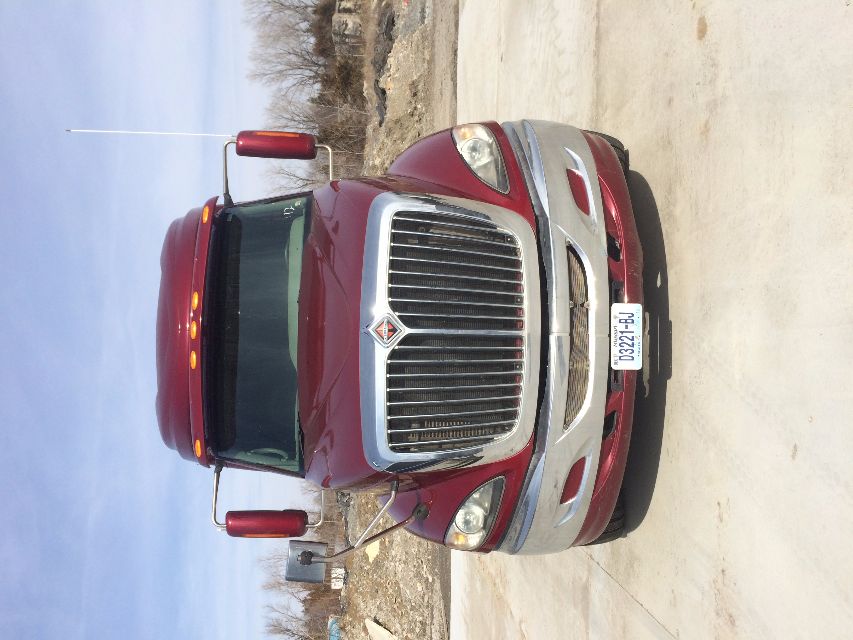 Front view of a burgundy 2011 International Prostar truck with chrome grille and large bumper, day time, license plate visible.