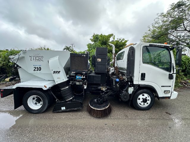 Isuzu NPR-HD sweeper truck side view showing front cab and mounted street sweeper body with large cylindrical brush and rear hopper.