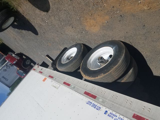 Trailer wheels of a utility cargo trailer with dual rear axles visible under a box trailer.