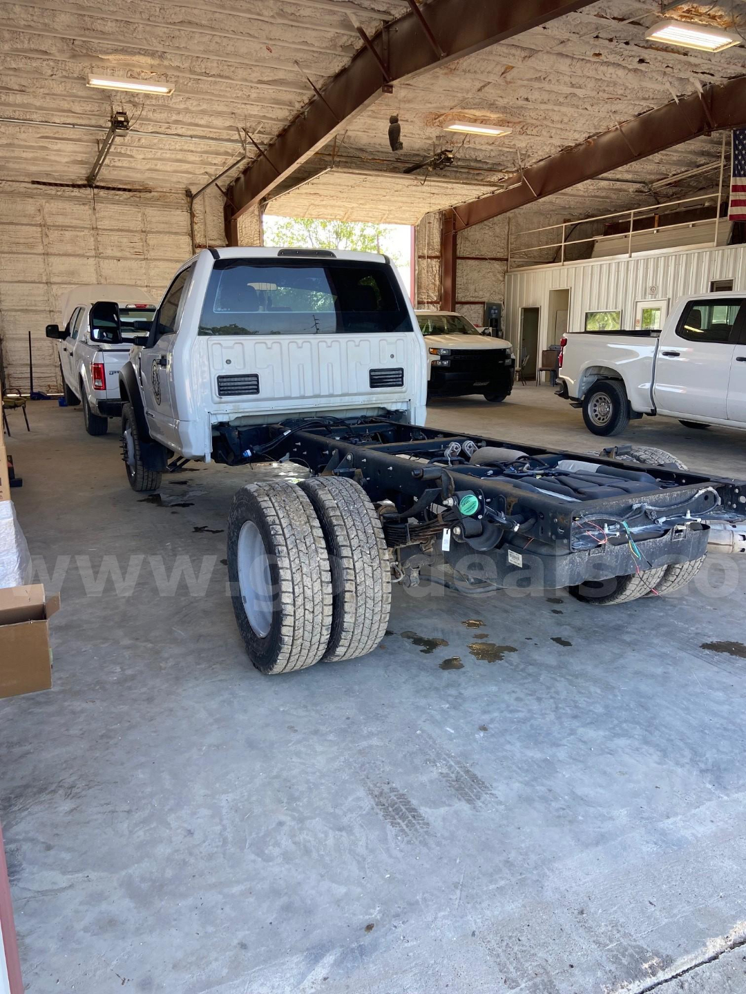 Cab and chassis Ford F-450 with rear chassis exposed, dual rear wheels, white cab, in a workshop setting.