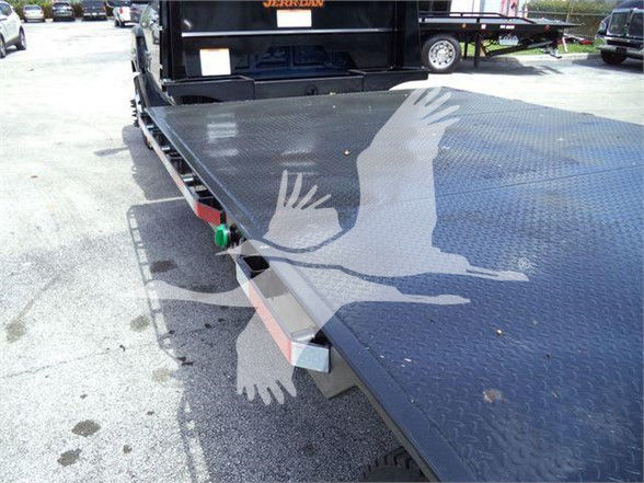 Chevrolet Silverado 6500HD tilt-bed flatbed rollback truck with diamond plate deck and ramp attachment points.