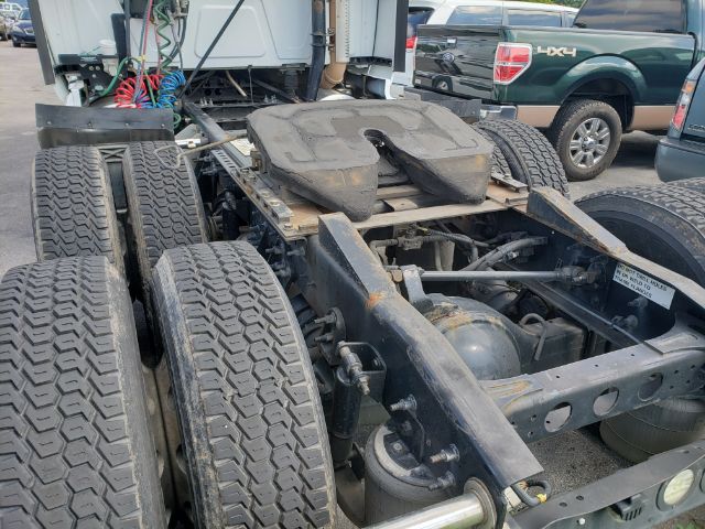 Tractor-trailer chassis with fifth wheel and dual rear axle showing tires, frame, and cab in background.