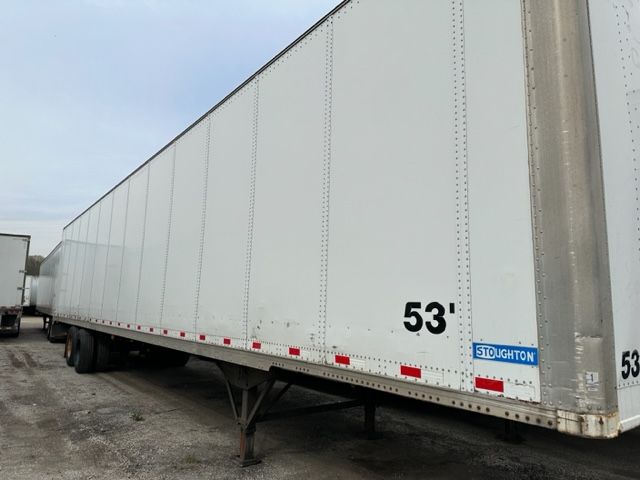 Trailer side view showing 53' Stoughton dry van with blue Stoughton plate and reflective safety tape.