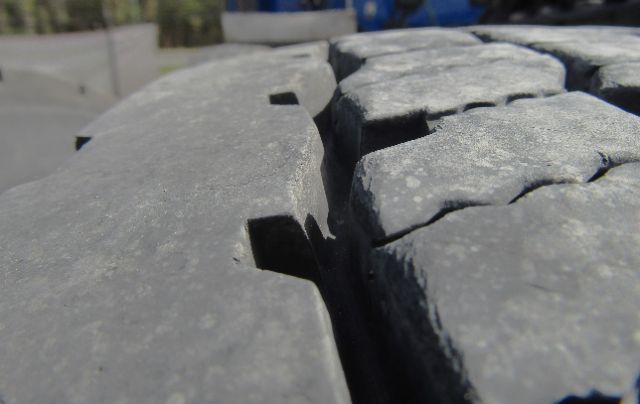 Close-up of a tire tread on a Kenworth truck showing cracked rubber and gaps.