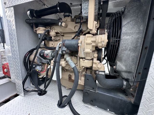 GMC W5500 vacuum truck engine bay showing hydraulic pump, hoses, radiator fan, and diesel engine components.