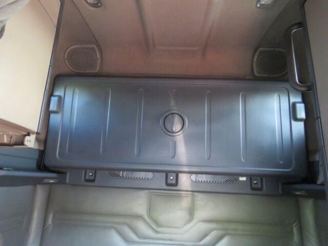 Truck cabin interior with metal bed floor and circular access hatch center, storage area; speaker grills visible on sides.