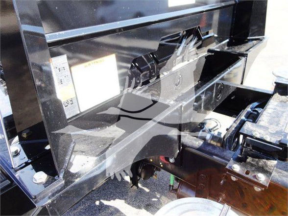 Truck hitch area showing frame rails and hydraulic components with skid plate and mounting hardware.
