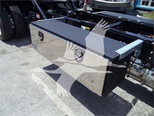 Mack MD6 truck chassis with a large rectangular aluminum toolbox mounted behind cab; visible tools and components around; reflective surface.
