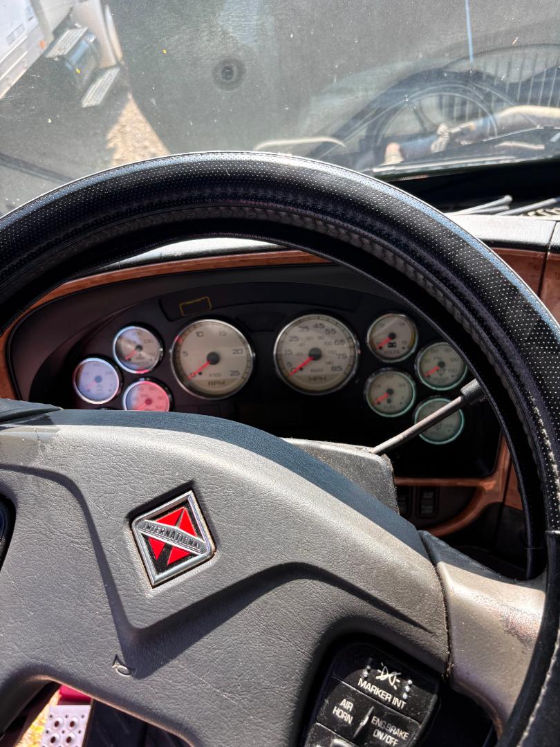 Interior of a 2016 International Prostar truck showing steering wheel with International diamond emblem and gauge cluster including speedometer and tachometer.
