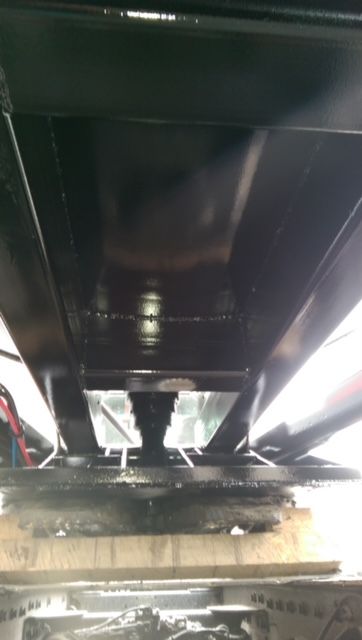 Underneath view of a black trailer frame showing structural beams and neck area, no readable labels visible.