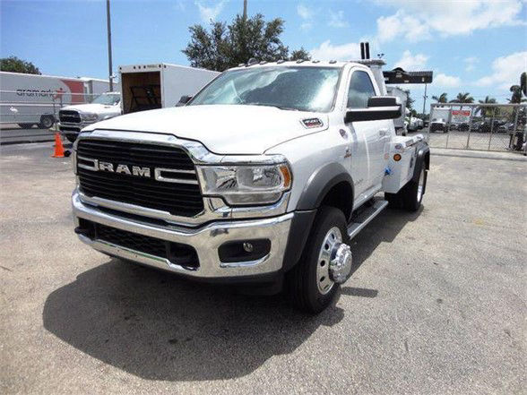 Ram 4500 tow truck front-left view with grille and DODGE RAM lettering, white cab, dual rear wheels, tow equipment in bed.